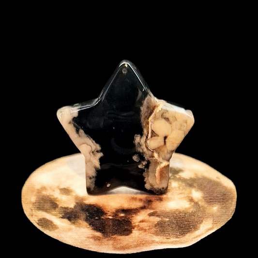 Polished black Flower Agate star carving with white blossom patterns, 42g, celestial crystal on moon backdrop.
