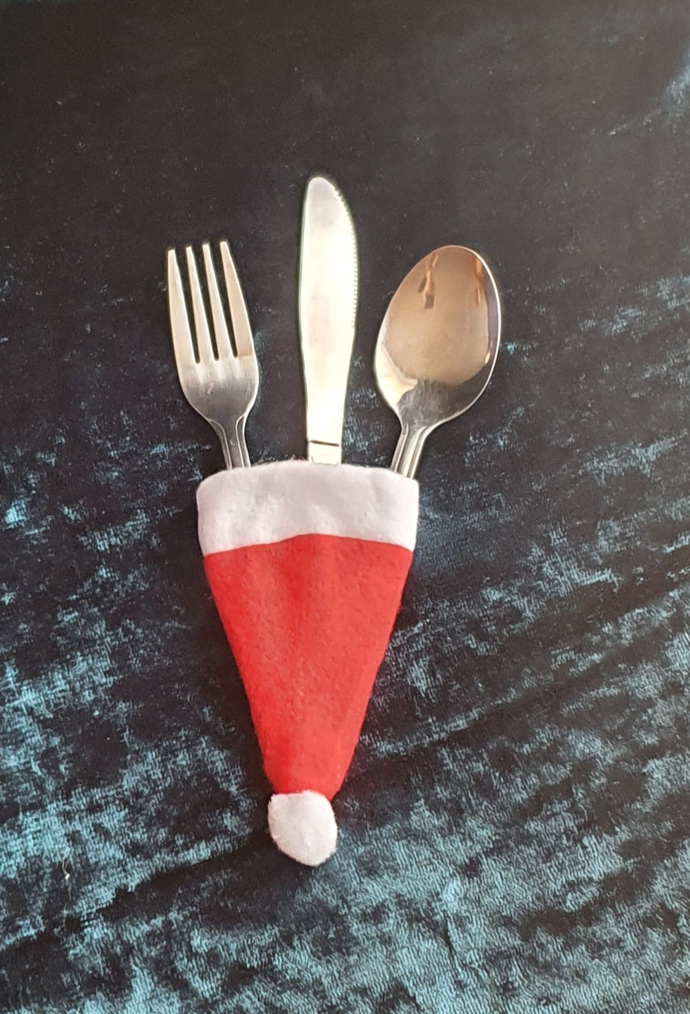 picture of four Santa hat cutlery covers with cutlery in - red and white in colour